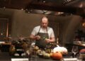 A chef cooking a Sunday roast around a table inside a cosy London gastropub