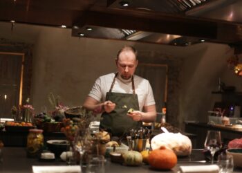 A chef cooking a Sunday roast around a table inside a cosy London gastropub