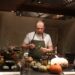A chef cooking a Sunday roast around a table inside a cosy London gastropub