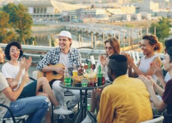 A group of friends enjoying an alfresco lunch on a sunlit terrace in London, raising glasses over a seasonal spread