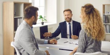 investor_reviewing_documents_papers_London - LONDONwebzine A property investor reviews documents at a desk, making decisions about London property in a modern office setting