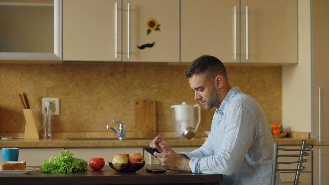 A man adding vegetable scraps to a countertop composter to reduce household waste in a compact flat