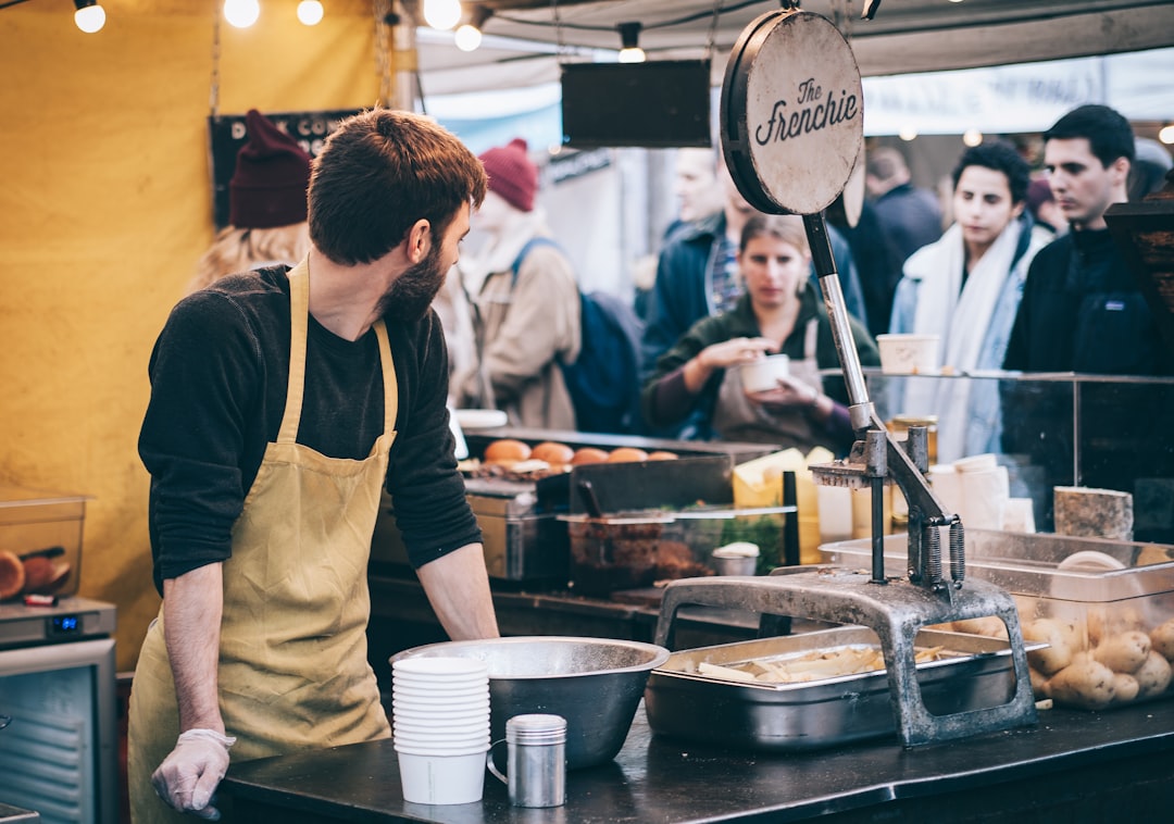 A male vendor serving customers at an outdoor food stall in one of London's East End neighbourhoods known for global cuisine