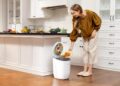 Une femme triant soigneusement les déchets ménagers dans les bacs de recyclage d'une petite cuisine d'appartement londonien