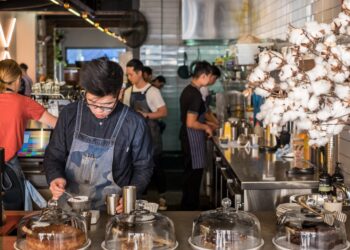 A barista crafts latte art at one of London's best independent coffee roasters, showcasing the specialty in every cup.