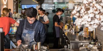 A barista crafts latte art at one of London's best independent coffee roasters, showcasing the specialty in every cup.