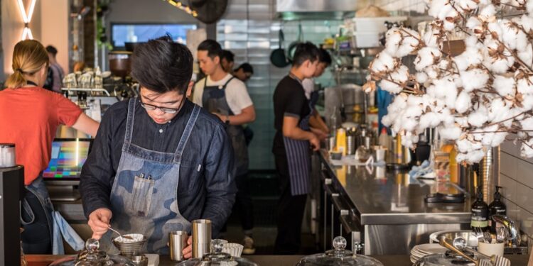 A barista crafts latte art at one of London's best independent coffee roasters, showcasing the specialty in every cup.