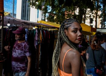 A Ghanaian community market trader in London arranges traditional fabric and food at an outdoor stall