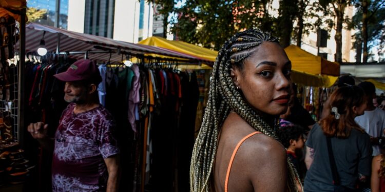 black-woman-market-vendor-unsplash - LONDONwebzine A Ghanaian community market trader in London arranges traditional fabric and food at an outdoor stall