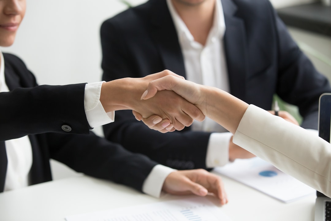 Two professionals shake hands after agreeing terms on a pre-seed funding deal at a London investment network event