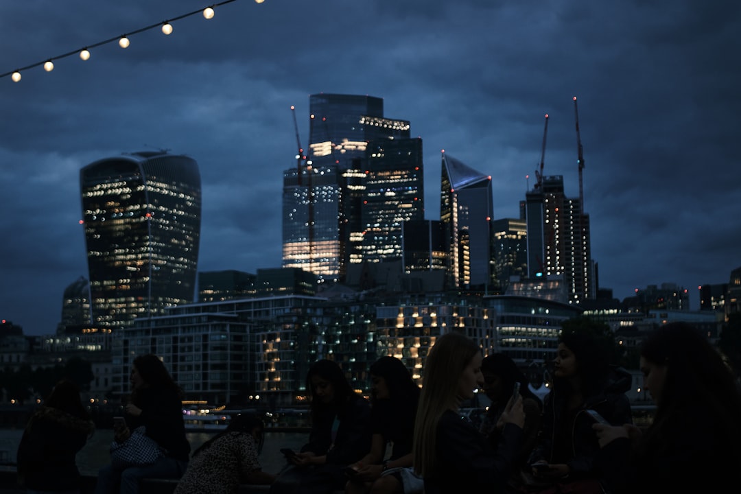 A couple enjoying cocktails on a rooftop bar with the London skyline behind them on a warm London summer evening