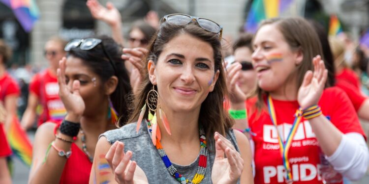 crowd-celebrating-pride-parade-london-unsplash - LONDONwebzine A joyful crowd of people waving rainbow flags during Pride in London along the parade route