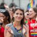 A joyful crowd of people waving rainbow flags during Pride in London along the parade route