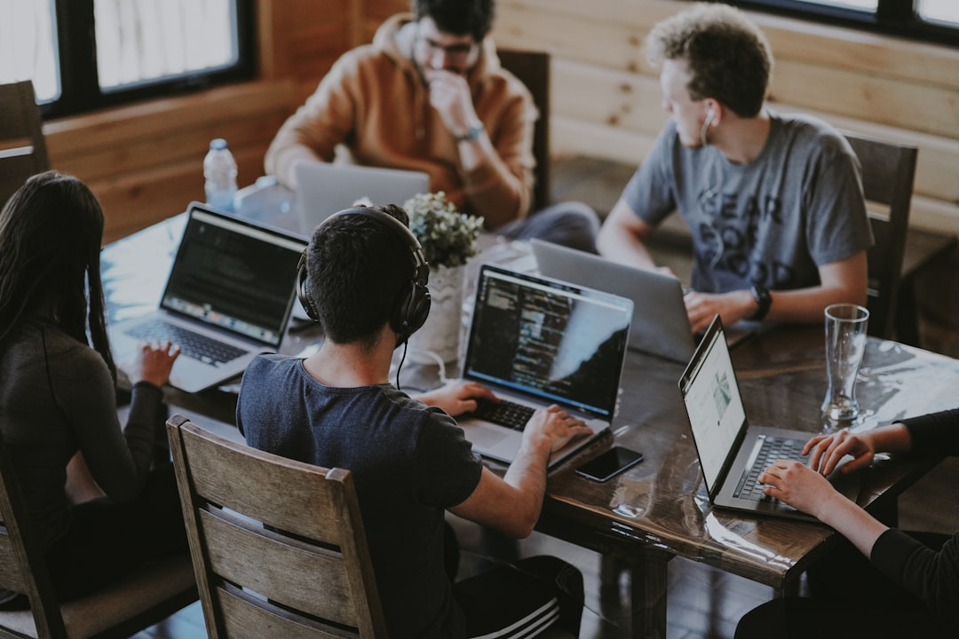 A diverse team of founders collaborates on laptops during a fintech accelerators cohort session in a London co-working space.