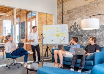 A London startup founder presents a pre-seed funding pitch to a group of angel investors in a modern meeting room