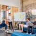 A London startup founder presents a pre-seed funding pitch to a group of angel investors in a modern meeting room