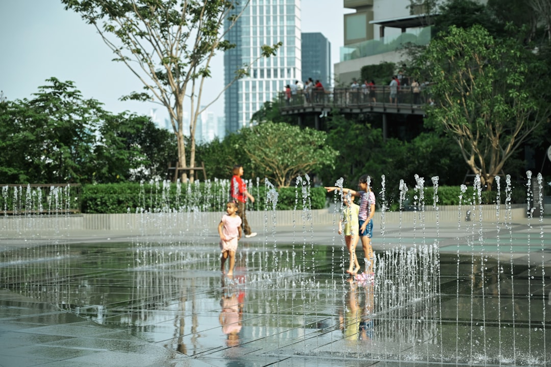 Children laughing and splashing in a free city play fountain, a beloved free outdoor activity for London kids on summer days
