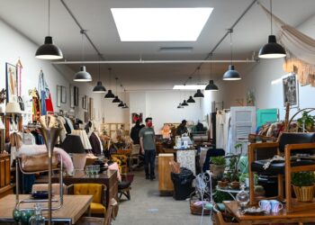 A man examining second-hand chairs at a London warehouse, exploring ethical furniture sourcing in the city.