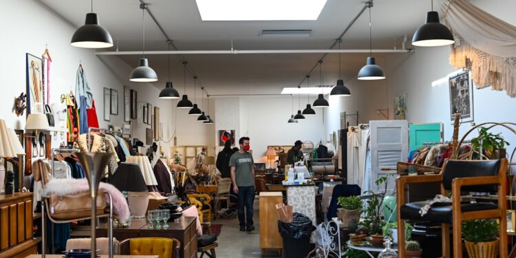 person-shopping-vintage-furniture-shopping-unsplash - LONDONwebzine A man examining second-hand chairs at a London warehouse, exploring ethical furniture sourcing in the city.