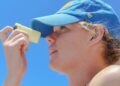 woman-applying-sunscreen-unsplash - LONDONwebzine A woman applying skin protection SPF on her face on a sunny London street