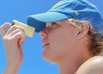A woman applying skin protection SPF on her face on a sunny London street