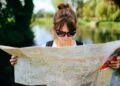woman-holding-a-map-unsplash - LONDONwebzine A traveller smiling inside a free London museum during a budget London weekend visit