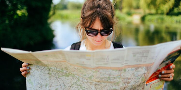 woman-holding-a-map-unsplash - LONDONwebzine A traveller smiling inside a free London museum during a budget London weekend visit