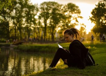 A woman relaxing on the grass at golden hour during a London summer evening in one of the city's Royal Parks