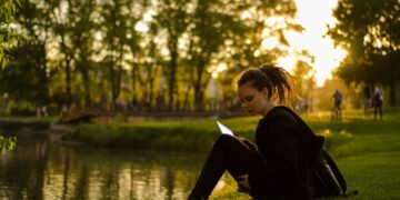 woman-picnic-park-sunset-unsplash - LONDONwebzine A woman relaxing on the grass at golden hour during a London summer evening in one of the city's Royal Parks