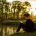 woman-picnic-park-sunset-unsplash - LONDONwebzine A woman relaxing on the grass at golden hour during a London summer evening in one of the city's Royal Parks