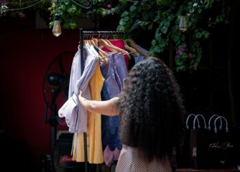 A woman in a linen outfit browsing an independent stall at a London market, building her sustainable wardrobe.