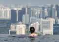 A woman swimming in one of London's rooftop pools with the city skyline visible through floor-to-ceiling windows