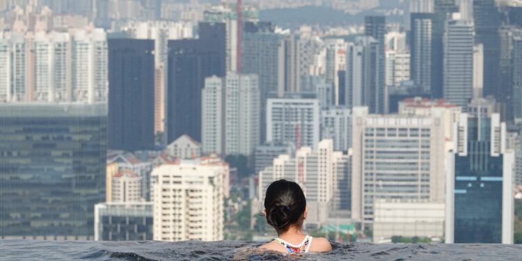 woman-swimming-rooftop-pool-city-view-unsplash - LONDONwebzine A woman swimming in one of London's rooftop pools with the city skyline visible through floor-to-ceiling windows