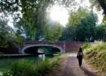 woman-walking-canal-path-unsplash - LONDONwebzine A woman walks along London's canal towpaths on a sunny summer morning with narrowboats moored behind her