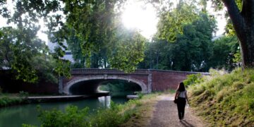 woman-walking-canal-path-unsplash - LONDONwebzine A woman walks along London's canal towpaths on a sunny summer morning with narrowboats moored behind her