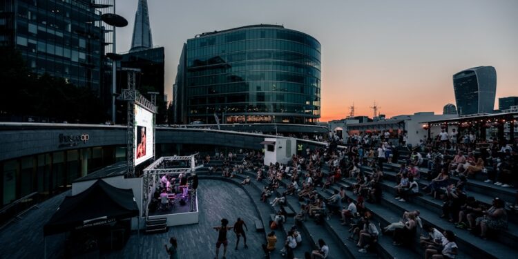 audience-watching-outdoor-theatre-london-park-unsplash - LONDONwebzine A crowd of people watching a free outdoor theatre performance in a London park during summer