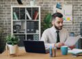 business-owner-reviewing-lease-documents-unsplash - LONDONwebzine A business owner carefully reviewing a commercial lease agreement in a bright London studio space