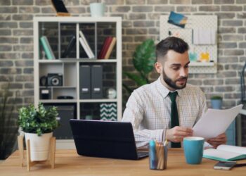 A business owner carefully reviewing a commercial lease agreement in a bright London studio space
