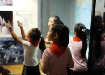 A young girl reaches out to touch a dinosaur fossil display inside one of London's top children's museums