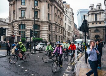 A group of beginners setting off on a road cycling club ride through a London park on a sunny morning
