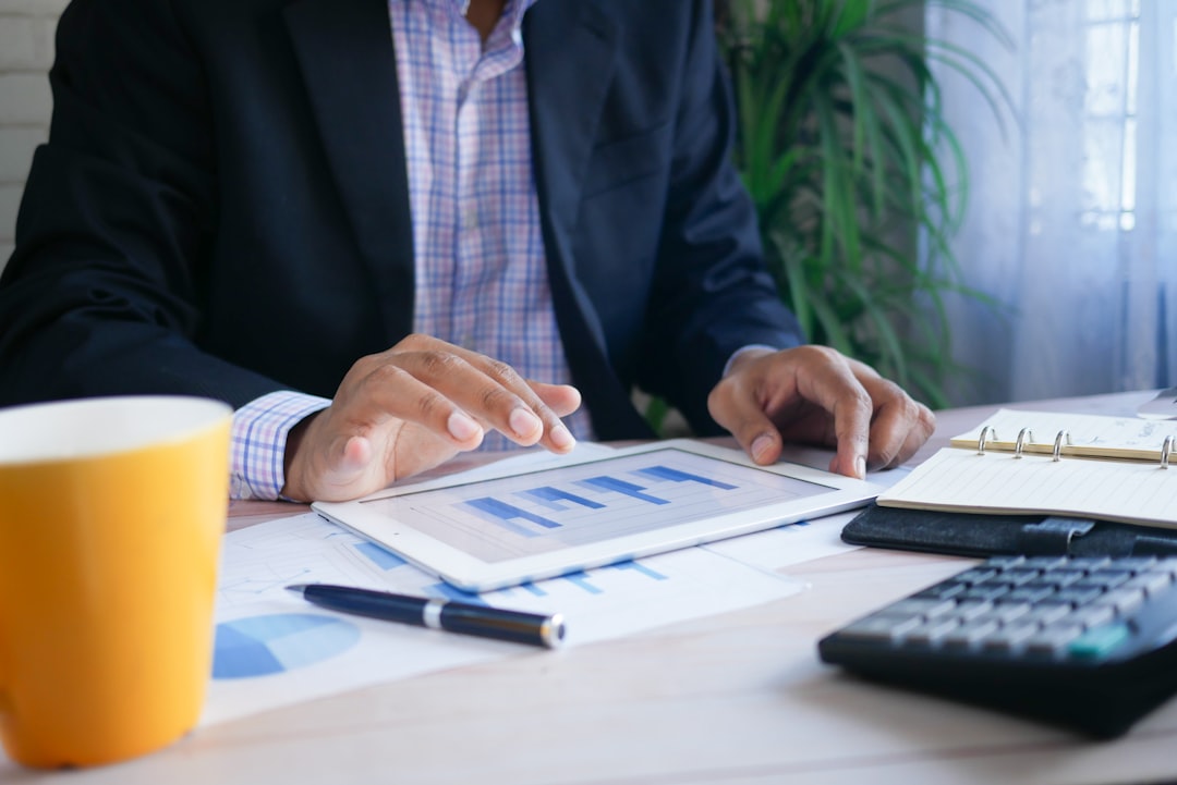 An investor at a London desk reviews documents and a laptop screen while managing a stocks ISA portfolio