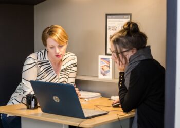 A London finance director conducts a business audit at her office desk in the City, reviewing financial records before Q4.