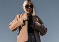 person-layering-jacket-unsplash - LONDONwebzine A woman in London adjusts her jacket layers, ready for a day of unpredictable August wear in the city.