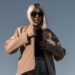 person-layering-jacket-unsplash - LONDONwebzine A woman in London adjusts her jacket layers, ready for a day of unpredictable August wear in the city.
