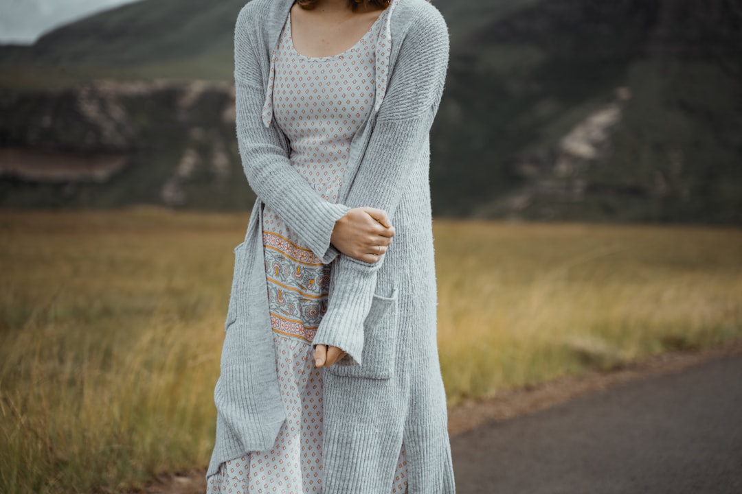 A person layering a knit jumper over a summer dress to adapt their London wardrobe for cooler autumn weather