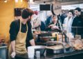 A vendor hands a customer fresh street food at Borough Market, one of London's most celebrated street food destinations.