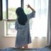 A woman standing by a bright London window in the morning, building a healthy sleep routine through early light exposure
