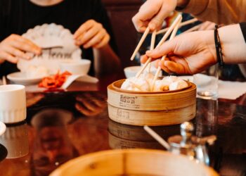A woman smiling while sharing dim sum dishes with friends at a London Cantonese restaurant