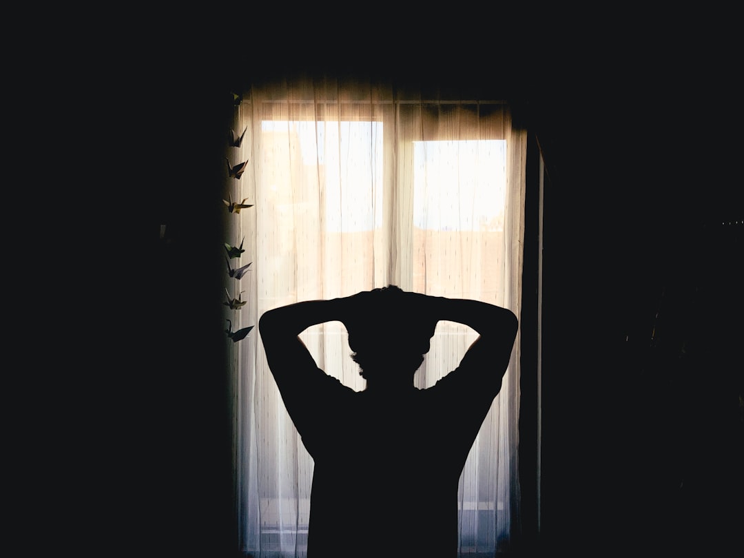 A woman resting in a darkened room with blackout blinds, supporting her sleep routine against London's late-summer light