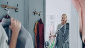 A woman reviewing her London wardrobe items on a bed, preparing for a seasonal transition from summer to autumn
